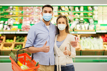 Image showing couple in masks with food basket at grocery store