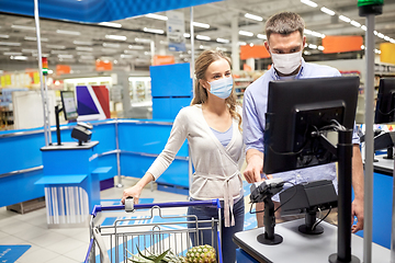 Image showing couple in masks buying food at store cash register