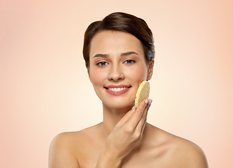 Image showing young woman cleaning face with exfoliating sponge