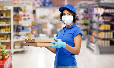 Image showing delivery woman in mask with pizza boxes at store