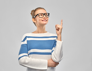 Image showing happy teenage girl in glasses pointing finger up