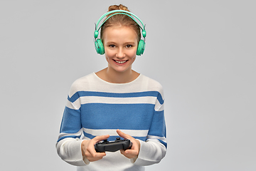 Image showing happy teenage girl with gamepad playing video game