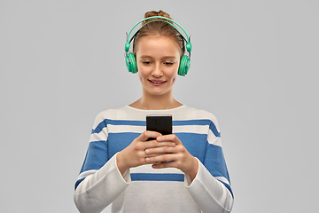 Image showing smiling teenage girl in headphones with smartphone