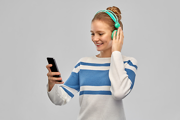 Image showing smiling teenage girl in headphones with smartphone