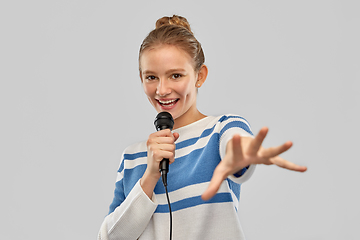 Image showing smiling teenage girl with microphone singing