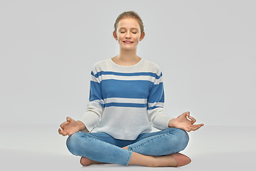 Image showing smiling teenage girl meditating in lotus pose