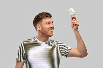 Image showing smiling young man holding lighting bulb