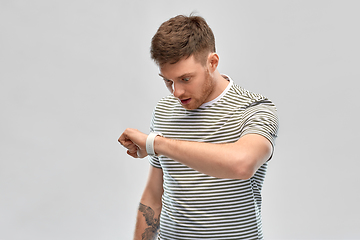 Image showing surprised young man looking at smart watch