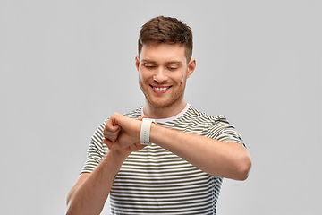 Image showing smiling young man looking at smart watch