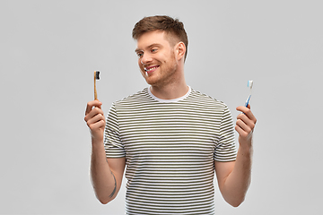 Image showing man comparing wooden and plastic toothbrush