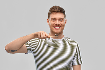 Image showing smiling man with toothpaste on wooden toothbrush