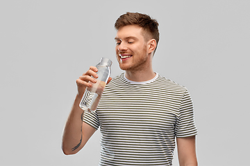 Image showing happy smiling man drinking water from glass bottle