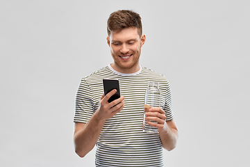 Image showing man with smartphone and water in glass bottle