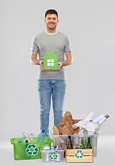 Image showing smiling young man with green house sorting waste