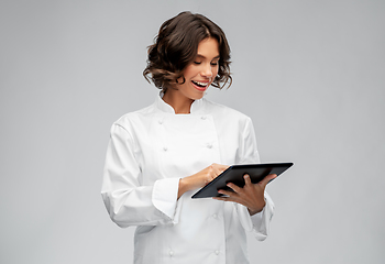 Image showing smiling female chef in toque with tablet computer