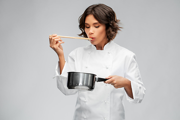 Image showing female chef with saucepan tasting food