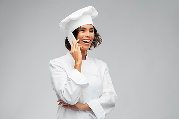 Image showing smiling female chef in toque calling on smartphone