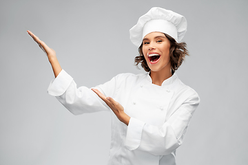 Image showing smiling female chef showing something with hands