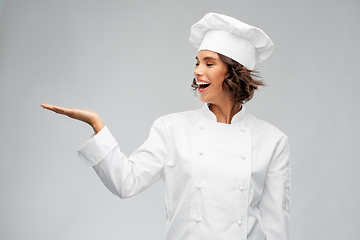 Image showing smiling female chef holding something on hand