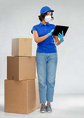 Image showing delivery woman in mask with boxes and tablet pc