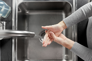 Image showing woman washing hands with liquid soap in kitchen