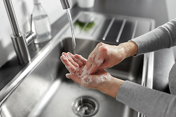 Image showing woman washing hands with liquid soap in kitchen