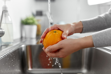 Image showing close up of woman washing orange fruit in kitchen