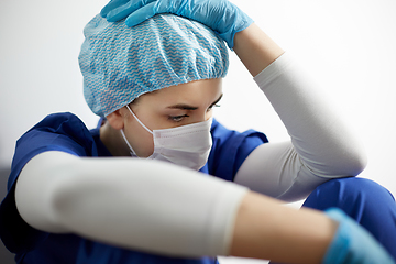 Image showing sad doctor or nurse in face mask holding to head