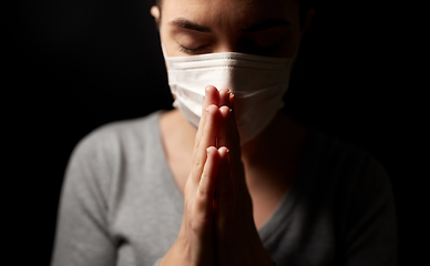 Image showing sick young woman in protective face mask praying