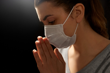 Image showing sick young woman in protective face mask praying