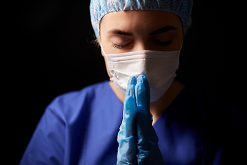 Image showing female doctor or nurse in face mask praying
