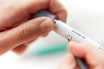 Image showing hand holding beaker with coronavirus blood test