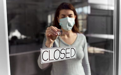 Image showing woman in mask hanging banner closed on door