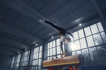 Image showing Little male gymnast training in gym, flexible and active