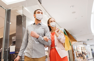 Image showing couple in medical masks with shopping bags in mall