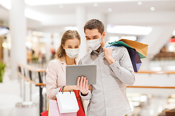 Image showing couple in masks with tablet pc in shopping mall