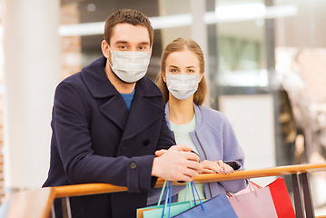 Image showing couple in medical masks with shopping bags in mall