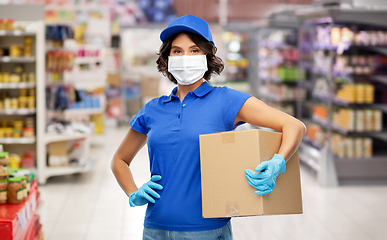 Image showing delivery woman in face mask holding box at store