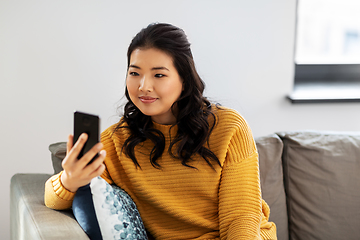 Image showing happy asian young woman with smartphone at home