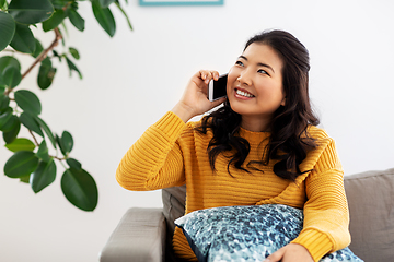 Image showing smiling asian woman calling on smartphone at home