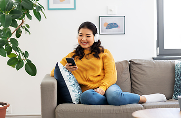 Image showing asian woman with headphones and smartphone at home