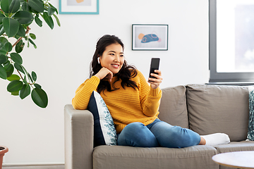 Image showing asian woman with earphones and smartphone at home