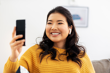 Image showing asian woman with earphones and smartphone at home