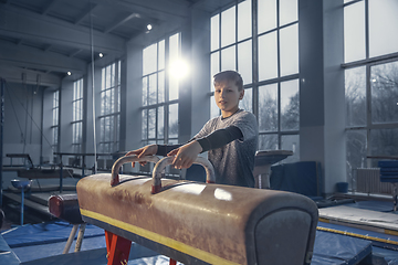 Image showing Little male gymnast training in gym, flexible and active