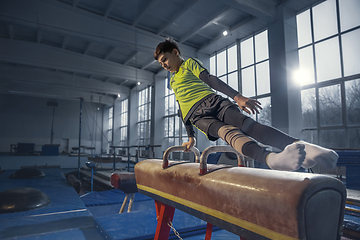 Image showing Little male gymnast training in gym, flexible and active