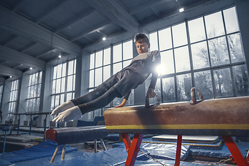 Image showing Little male gymnast training in gym, flexible and active