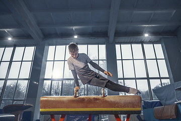 Image showing Little male gymnast training in gym, flexible and active