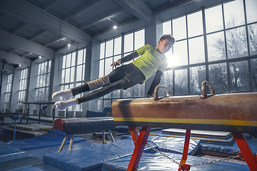 Image showing Little male gymnast training in gym, flexible and active