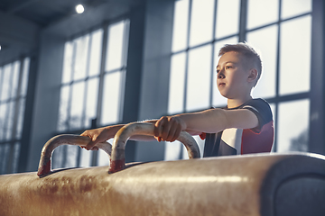 Image showing Little male gymnast training in gym, flexible and active