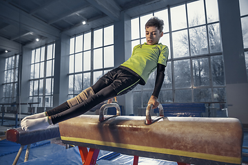 Image showing Little male gymnast training in gym, flexible and active